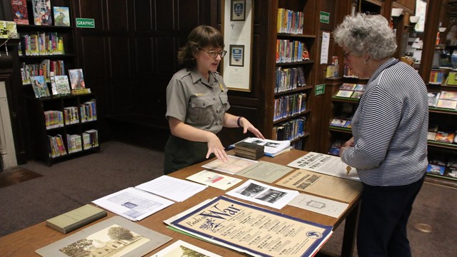 Ranger talking with visitor around table with information