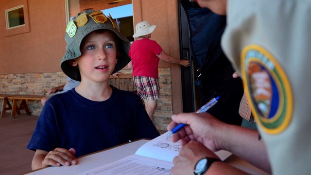 A Junior Ranger waits for his booklet to be looked over by a ranger