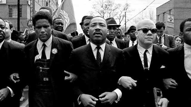 Historic photo of men marching arm and arm