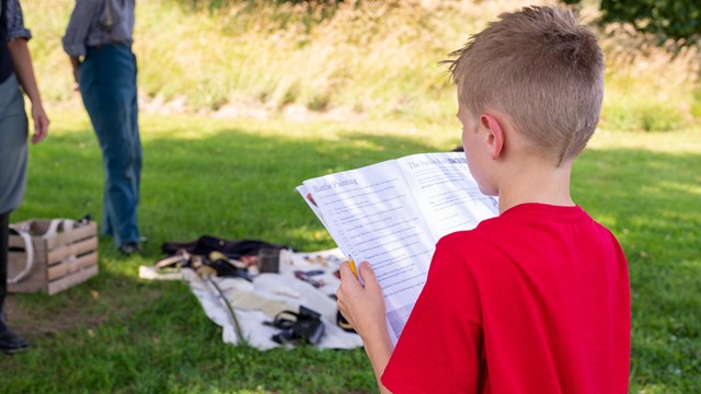 An 11 year old boy filling out a work book.