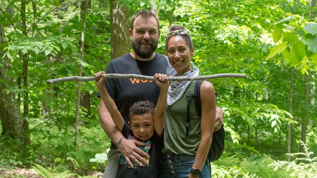 Two adults and a child pose for a photo on a trail