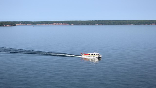 A white boat cuts through a calm Lake Superior