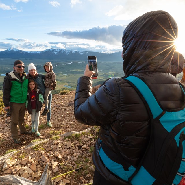 Someone taking a photo of a family standing by an overlook of a valley