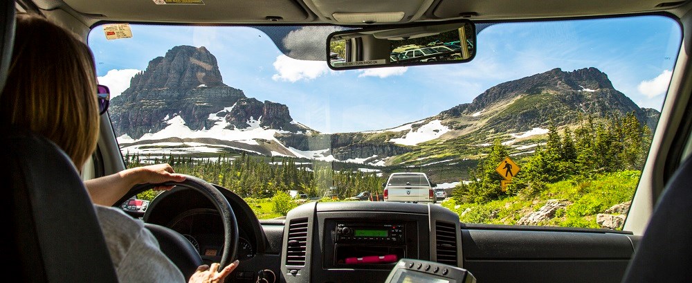 view of road and mountains looking over driver's shoulder out windshield