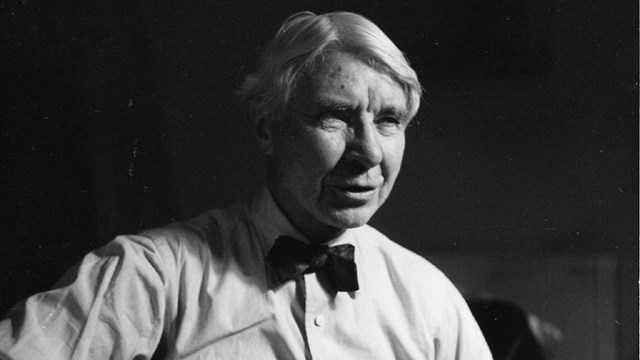 Black and white photo of Carl Sandburg holding a guitar