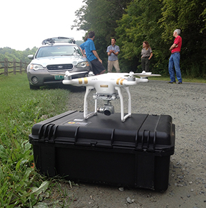 Close-up view of a quadcopter unmanned aircraft and three people.