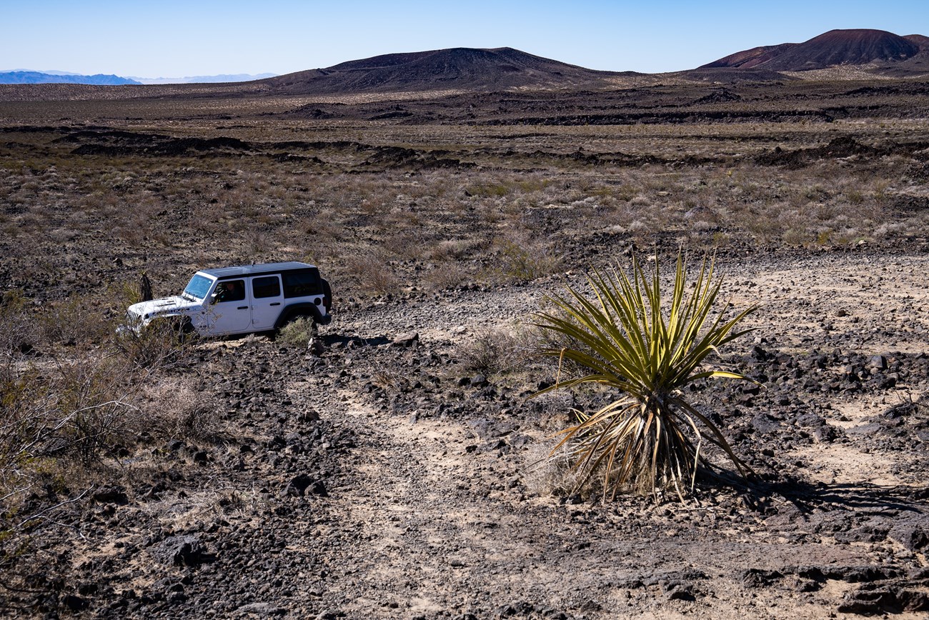 a white Jeep on rocky black lavabeds