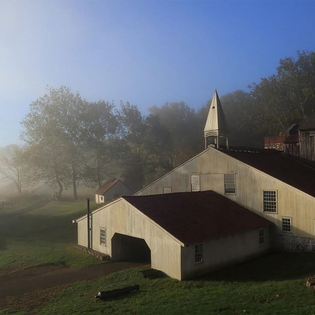 The large triangular cast house with a wide base and short pointed peak, sits in the fog.