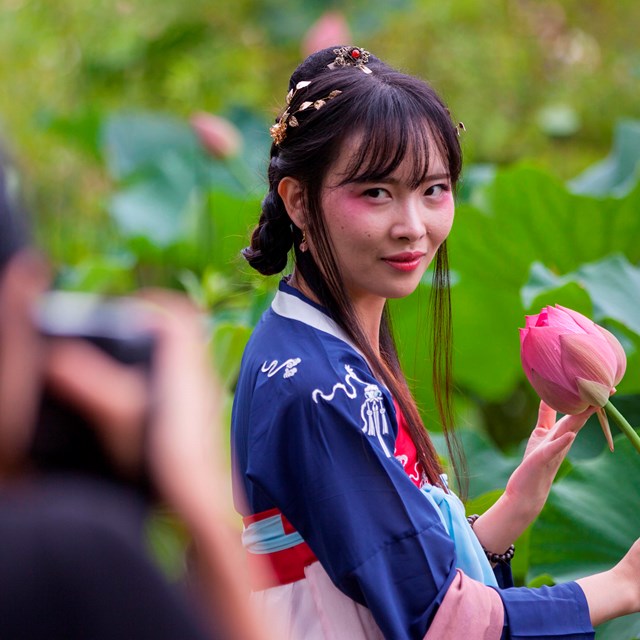 woman posing for picture holding a lotus 