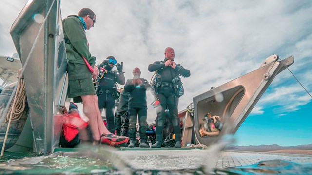 Several divers prepare to dive into a lake.