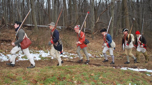 Soldier reenactors marching along a trail in the forest