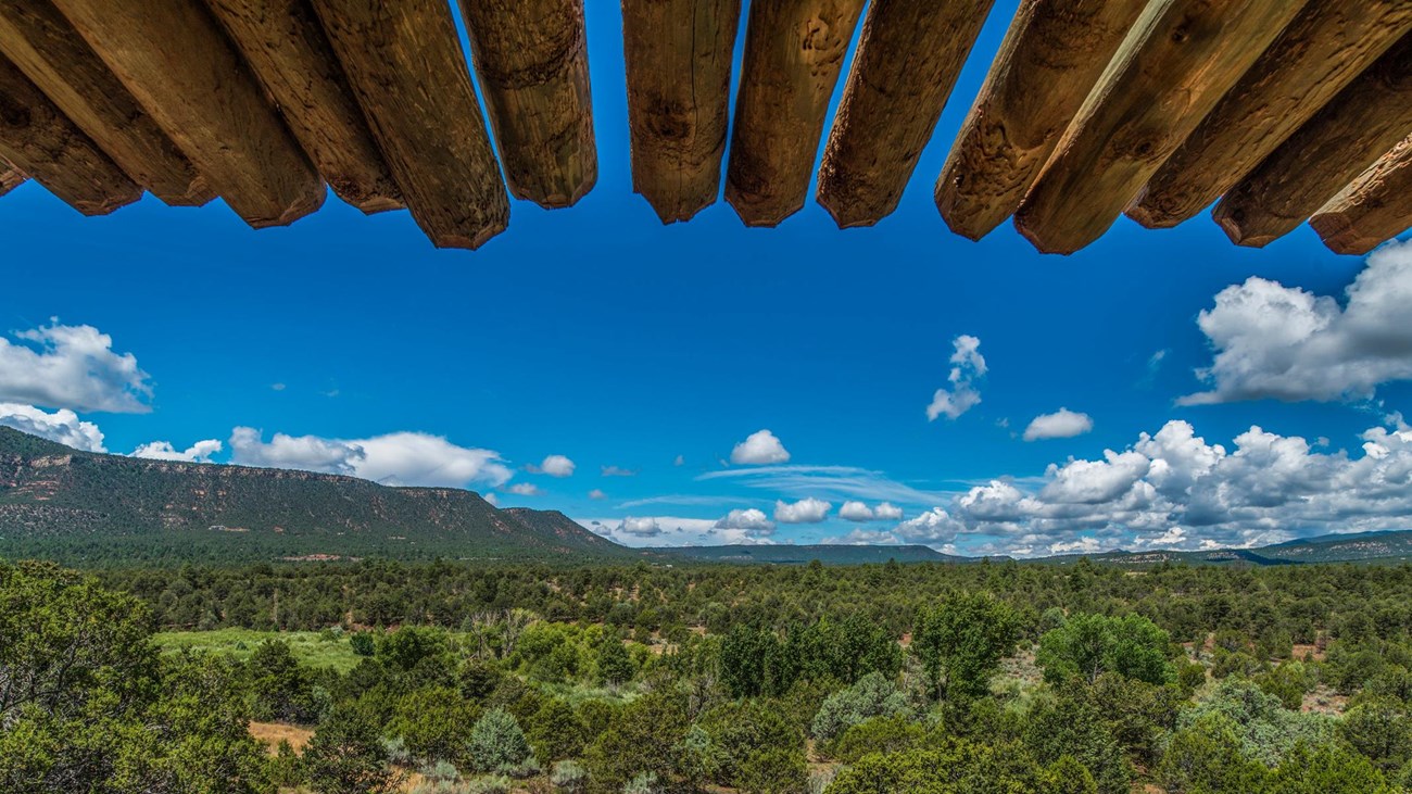 Wooden beams from the ramada frame view of mountains surrounding Glorieta pass.