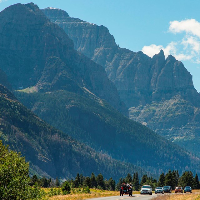 mountain on left in background, road in center with cars driving toward you