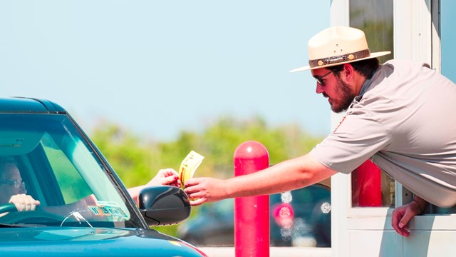 Fee ranger handing pass to visitor in vehicle.