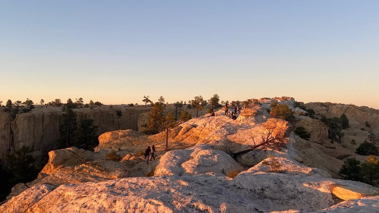 Many people walking across the top of a rock