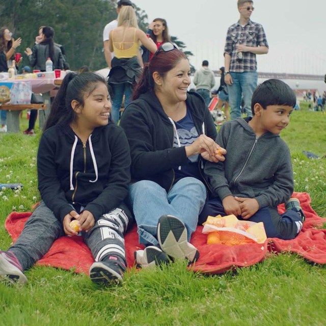 family shares red picnic blanket on crissy field