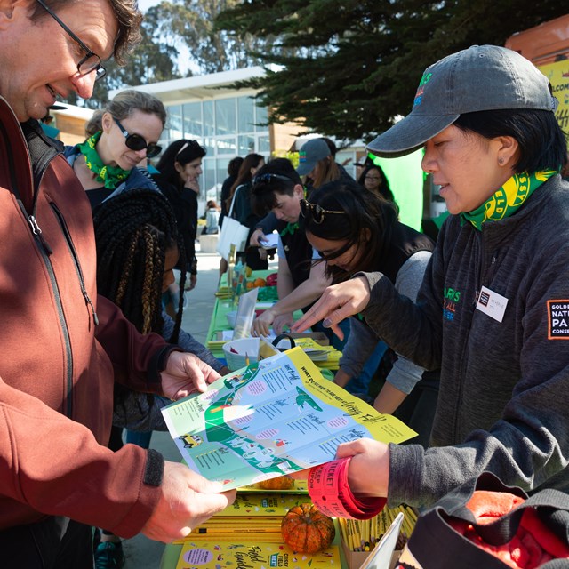 Person hands brochure to another person in line in front of Crissy Field