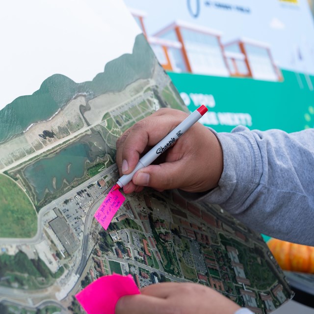 Hand writes on post-it notes over a map