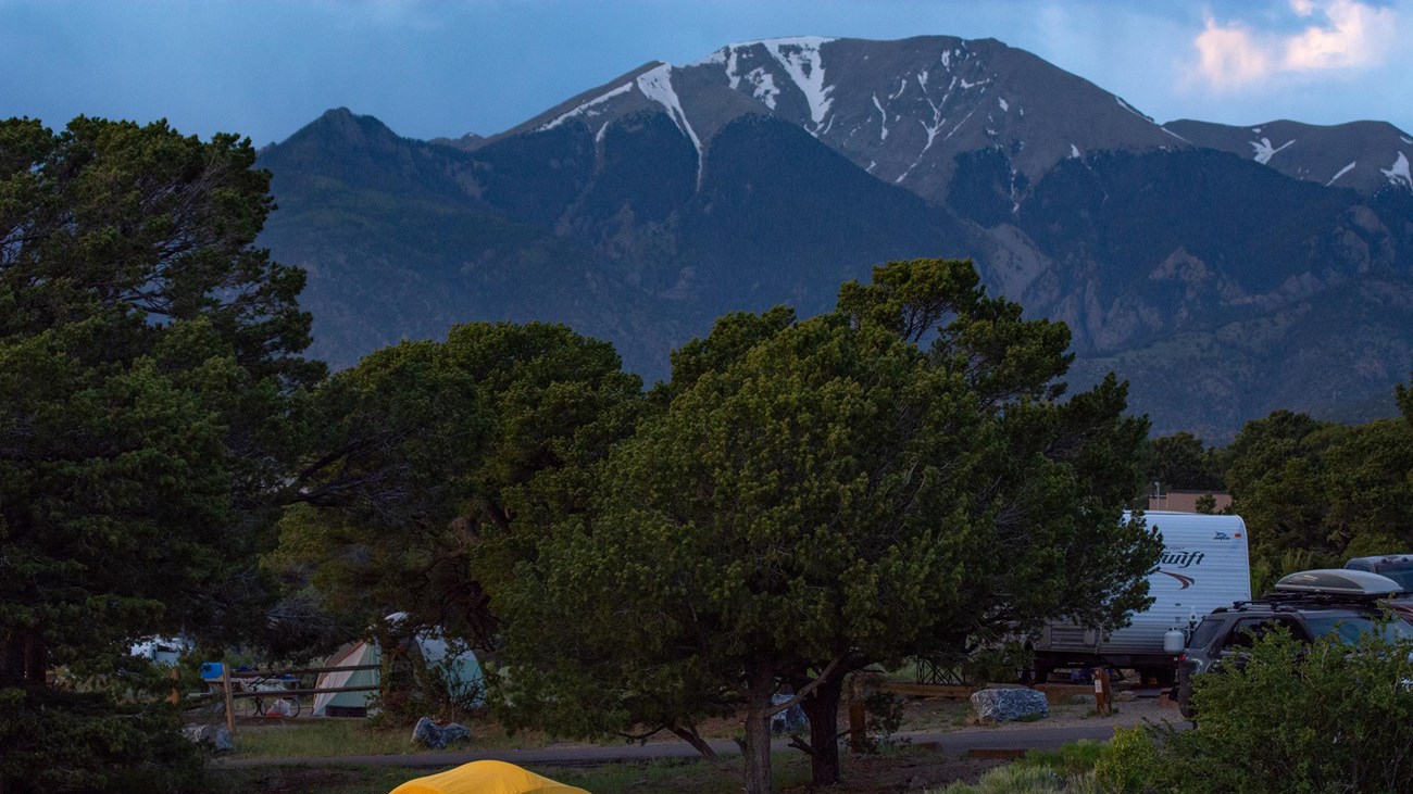 Tent and trailers among trees, mountain in background