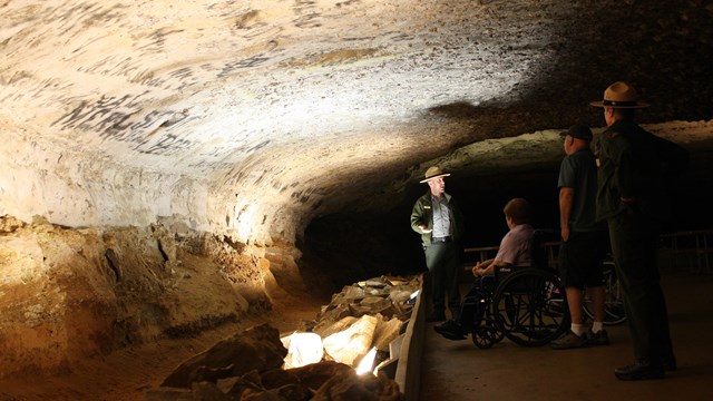 A group of visitors, one in a wheelchair, listen to a ranger.