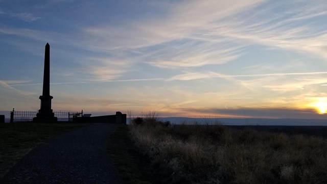 Whitman monument silhouetted against the sunset