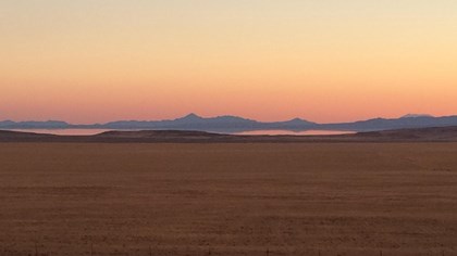 An orange and pink sky meet the top of distant mountains with the Great Salt Lake in the foreground.