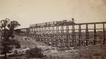 Sepia colored Locomotive traveling over Trestle over gorge