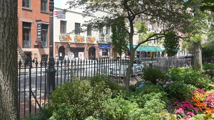 Brick building with iron fence and flowers out front