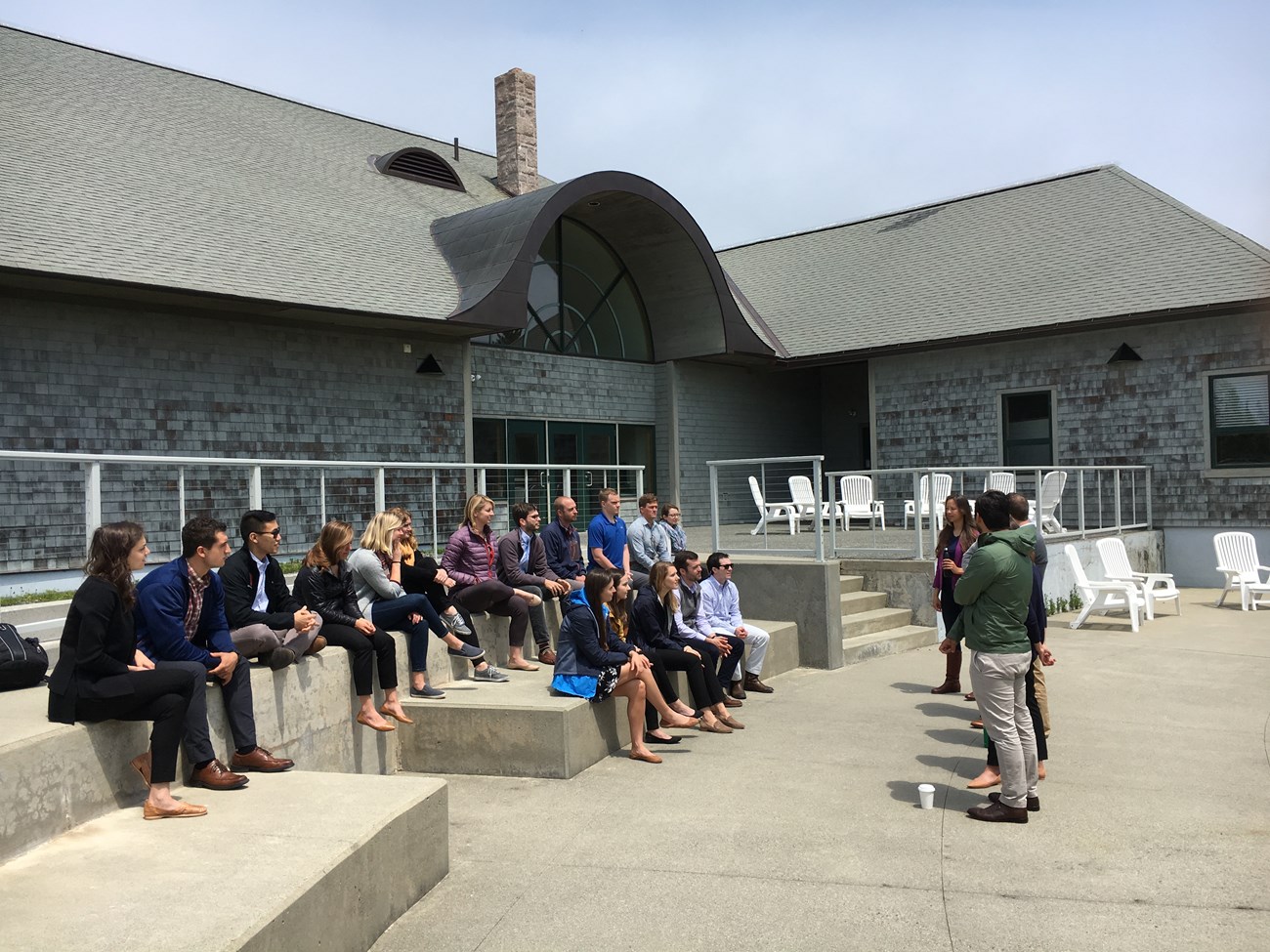 BPI program group listening to a speaker while seated outside a building