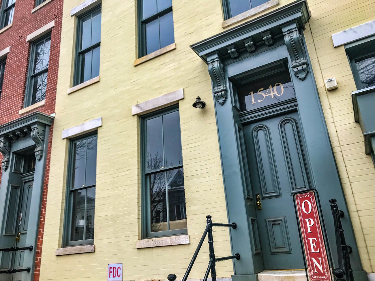 Three-story yellow townhouse with green trim