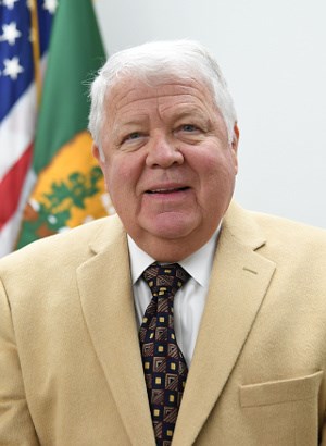 Deputy Director Dan Smith Man in suit posing in front of flag