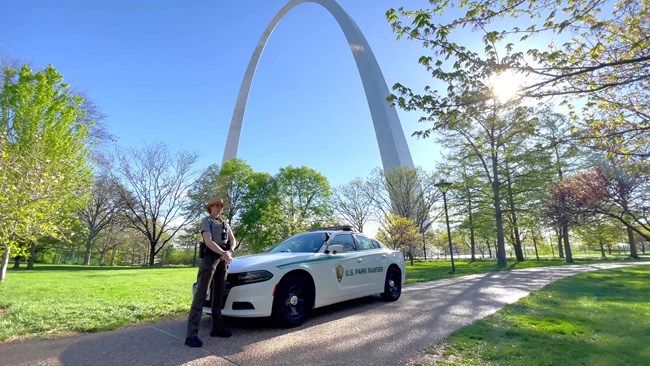 Law enforcement ranger standing next to a patrol vehicle with the Gateway Arch in the background