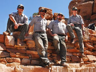 Four trail crew members sitting on rock wall Four trail crew members sitting on rock wall