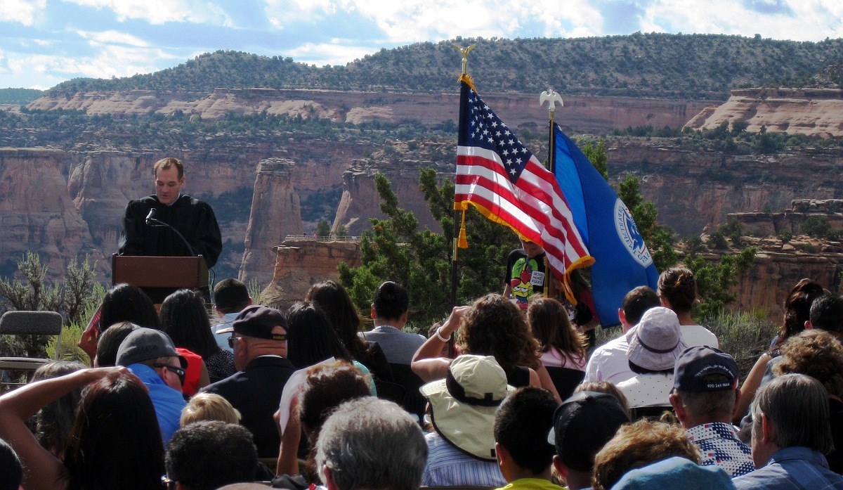 Male judge speaking to seated audience overlooking rocky canyon