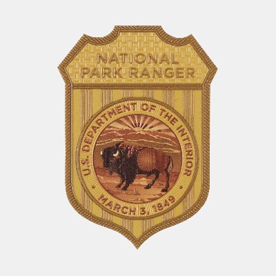 A yellow badge with the US Department of the Interior seal and the words National Park Ranger