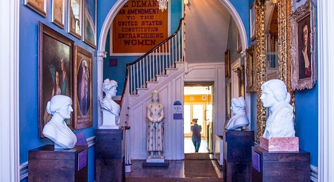 interior hallway at Belmont-Paul interior hallway and staircase with busts of famous suffragists and a 19th Amendment banner