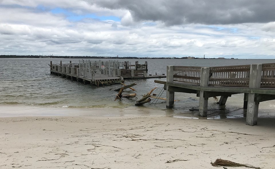 sections of a destroyed pier along a sandy beach