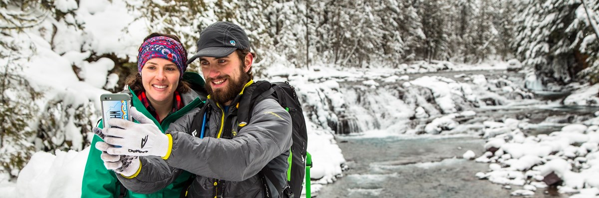 GLAC Sacred Dancing Cascades (NPS Jacob Frank) Two visitors taking a selfie by a frozen creek