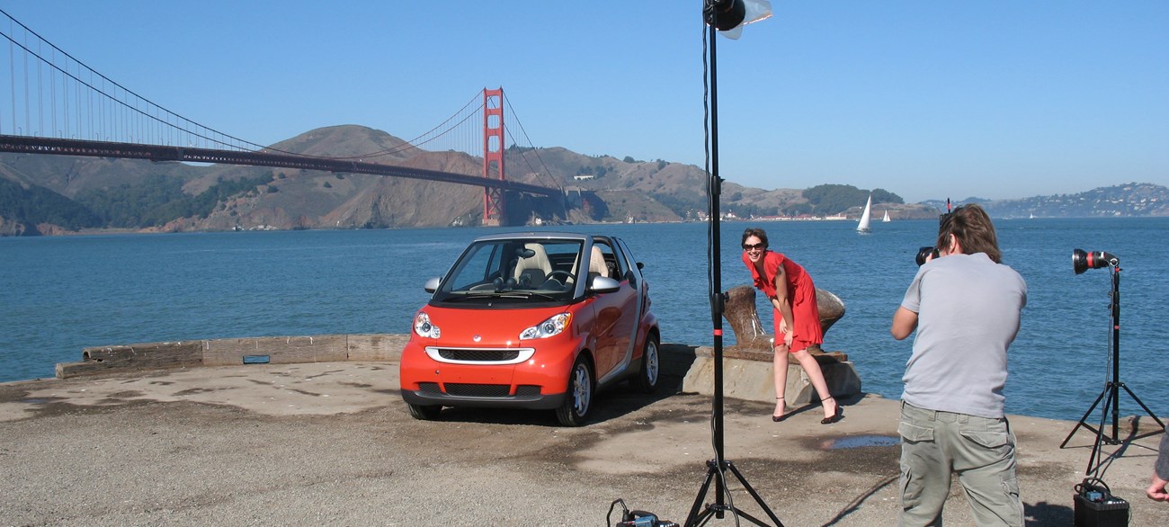 Photographer with a professional setup taking pictures of a model and car with the Golden Gate Bridge in the background
