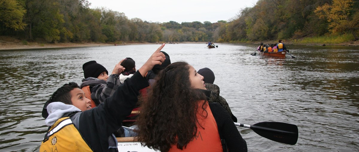 MISS Students Youth group on a canoe on a river looking and pointing at something in the sky