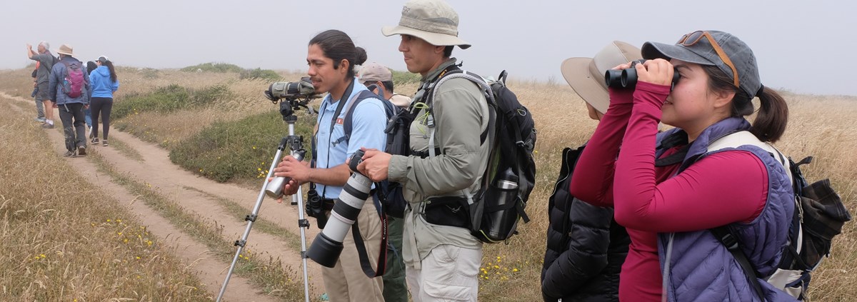 PORE LHIP Intern (NPS Diego Morales) Intern talking to visitors while birding in a wetland