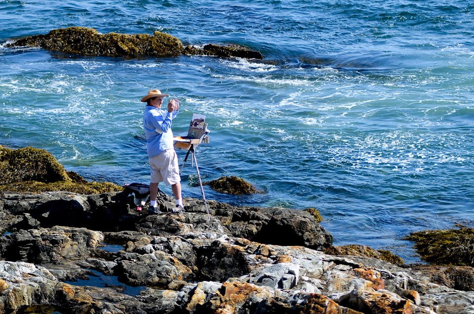 Painter with small easel works by open ocean