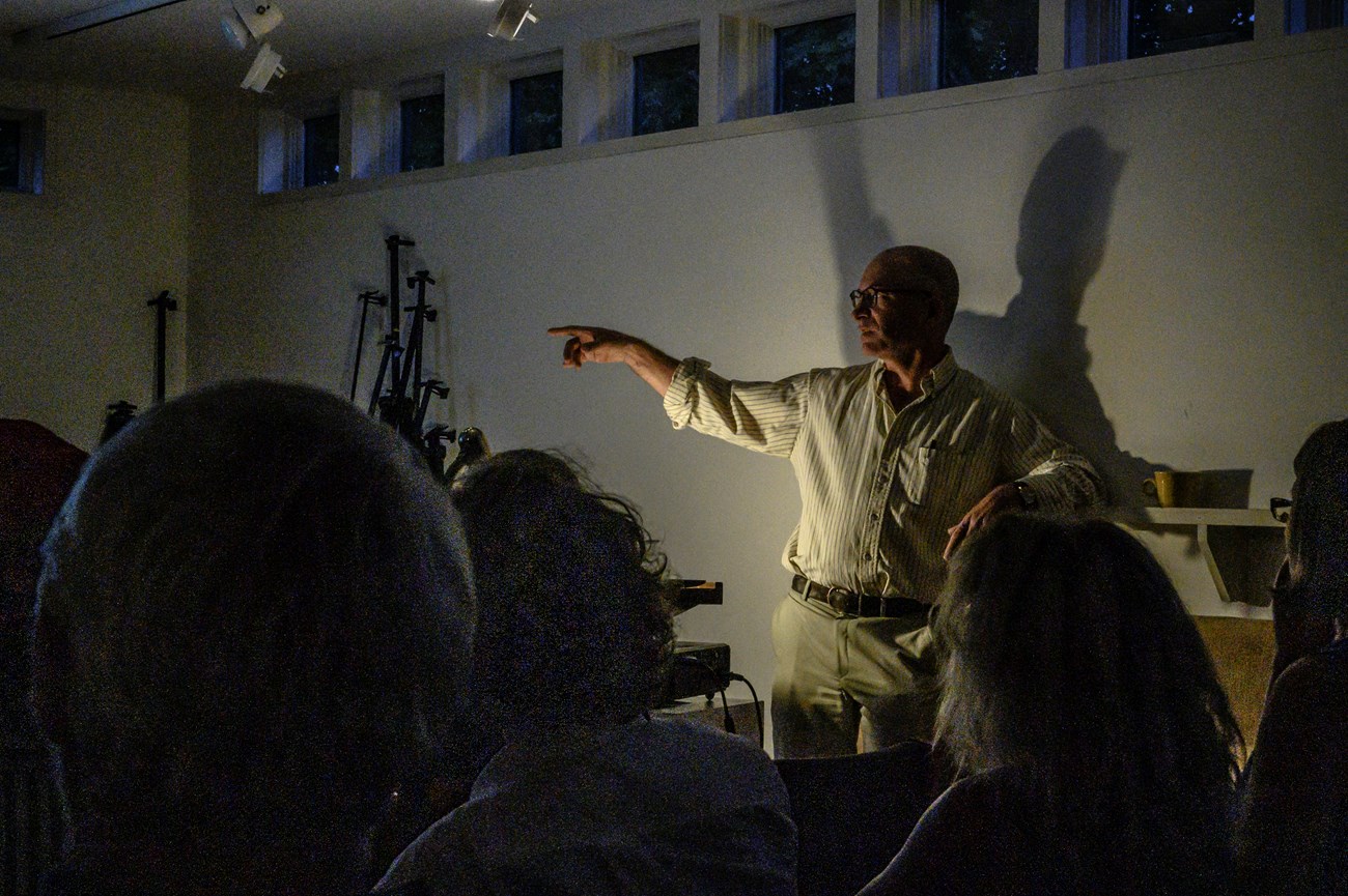 Man standing in dramatic light with shadow cast on wall behind him