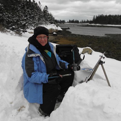 Woman bundled up in heavy winter clothing paints at an easel in a snow bank