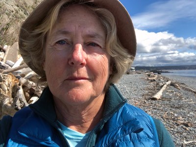 Woman on gravel beach strewn with driftwood