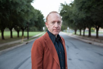 Portrait of a man standing in a tree-lined road