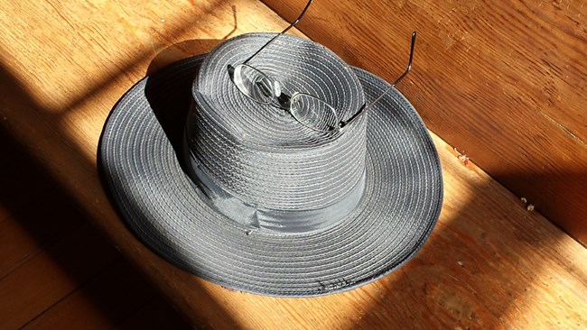 Dark wide brimmed hat on wood surface with eye glasses