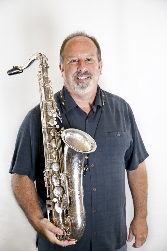 Man smile while holding a silver saxophone