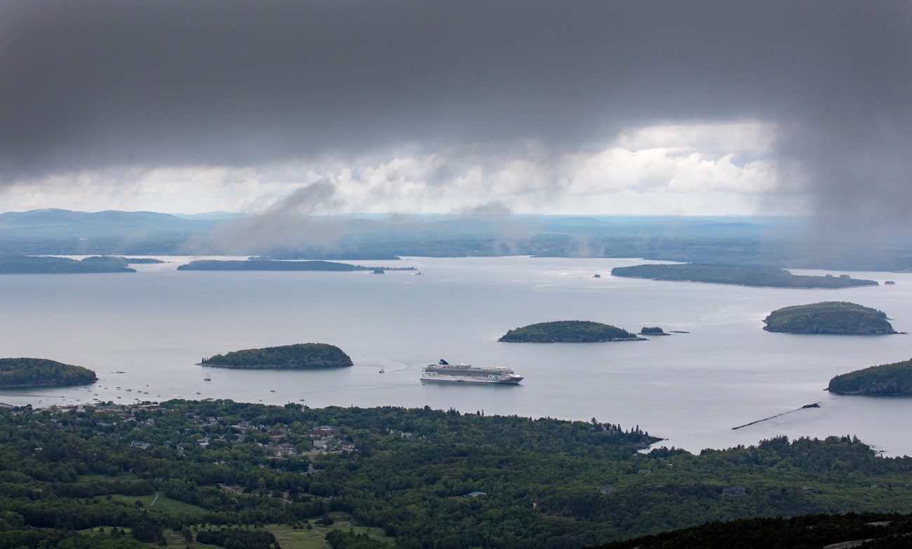 View from a mountain summit of islands and boats on the ocean.
