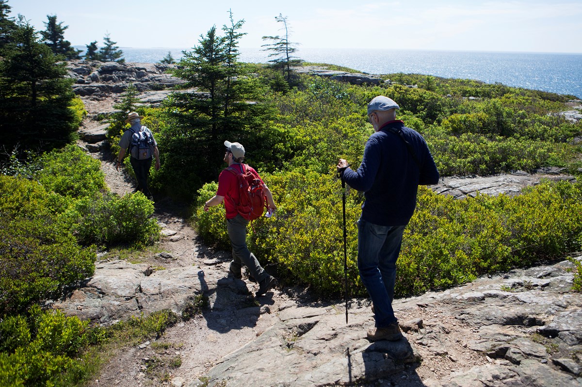 Three people hike along a coastal trail
